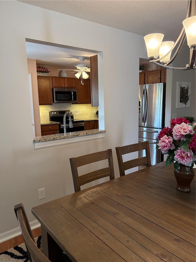 dining space featuring ceiling fan with notable chandelier and hardwood / wood-style flooring