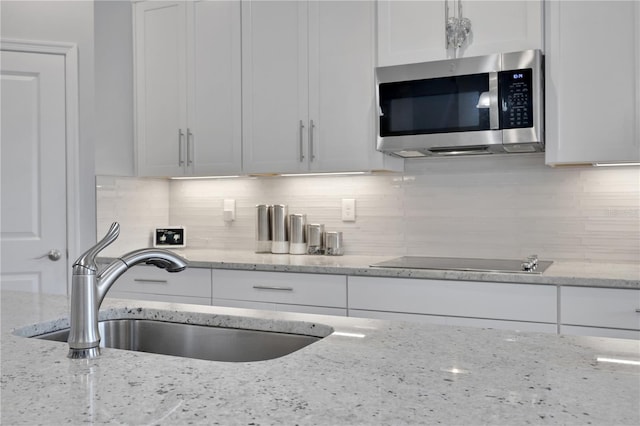 kitchen with black electric stovetop and light stone counters