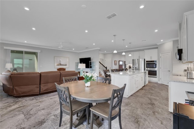 dining space with ceiling fan, sink, and crown molding