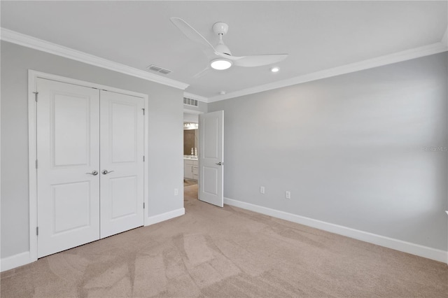 unfurnished bedroom featuring ceiling fan, light colored carpet, crown molding, and a closet