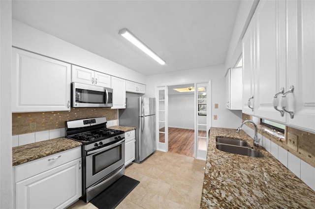 kitchen with white cabinetry, sink, tasteful backsplash, dark stone counters, and appliances with stainless steel finishes