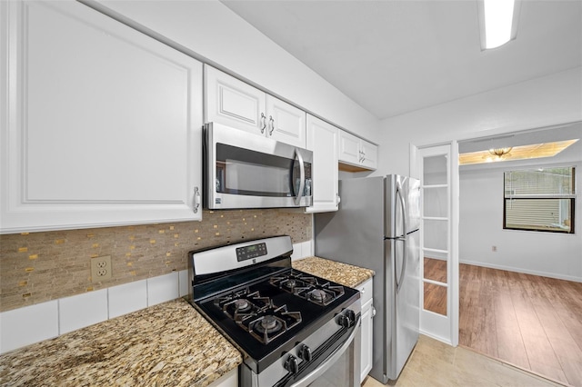 kitchen with stainless steel appliances, light tile patterned floors, tasteful backsplash, light stone counters, and white cabinets