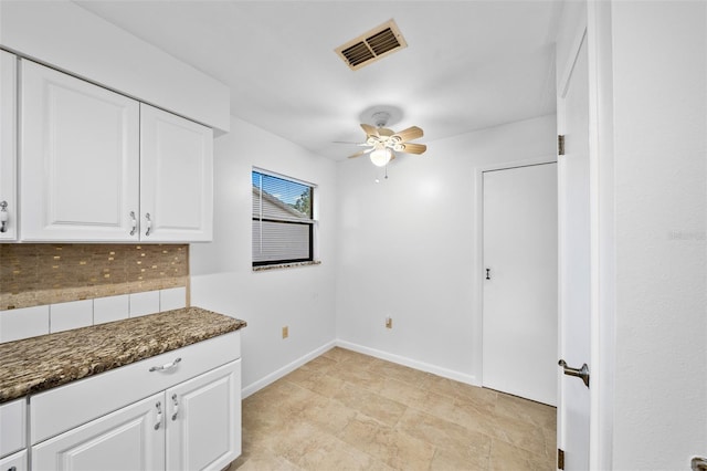 interior space featuring tasteful backsplash, dark stone countertops, ceiling fan, and white cabinets