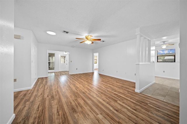 unfurnished living room with ceiling fan, light hardwood / wood-style floors, and a textured ceiling