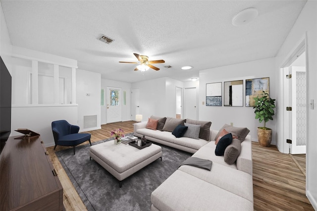 living room with a textured ceiling, ceiling fan, and dark wood-type flooring