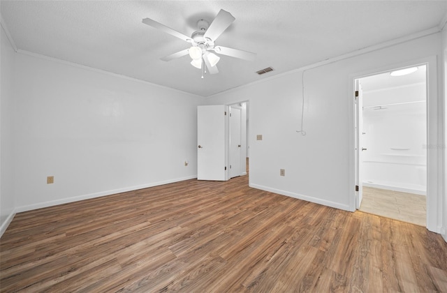 unfurnished bedroom with ceiling fan, wood-type flooring, crown molding, and connected bathroom