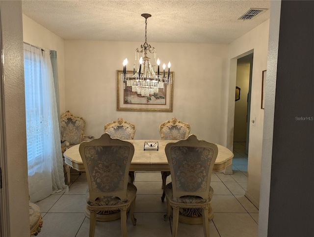 tiled dining space with a textured ceiling and an inviting chandelier