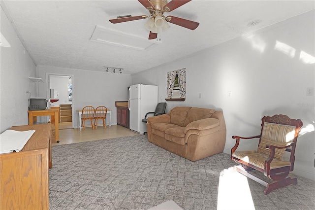 carpeted living room with ceiling fan, track lighting, and a textured ceiling