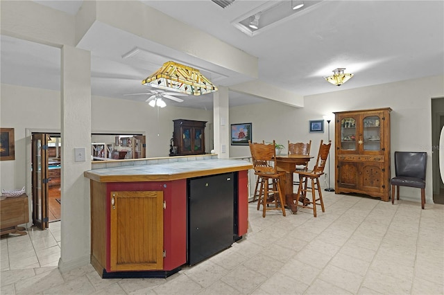 kitchen featuring tile countertops, ceiling fan, and fridge