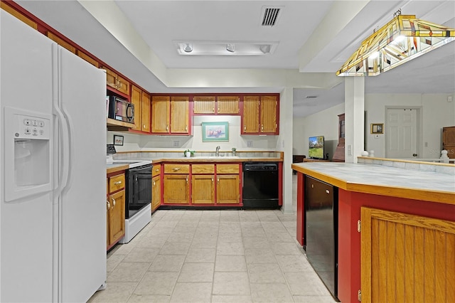 kitchen with pendant lighting, white appliances, and tile countertops