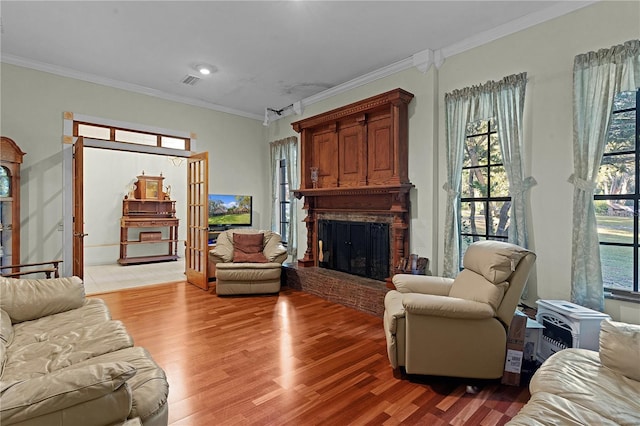 living room with light hardwood / wood-style floors, a stone fireplace, and ornamental molding