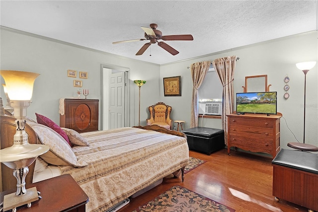 bedroom with a textured ceiling, ceiling fan, crown molding, cooling unit, and wood-type flooring