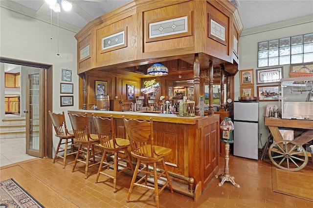 bar featuring ceiling fan, stainless steel fridge, light tile patterned flooring, and crown molding