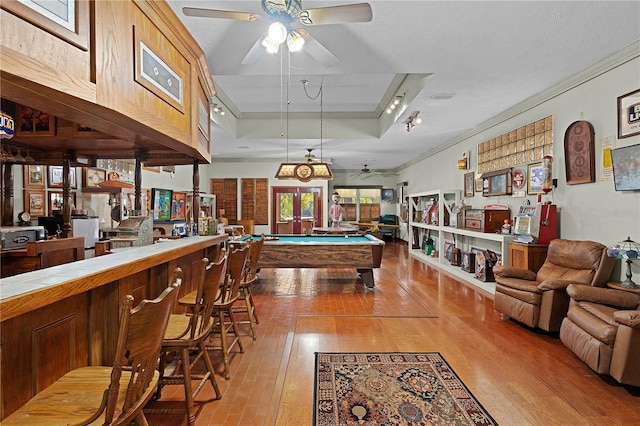 recreation room featuring a tray ceiling, crown molding, light hardwood / wood-style flooring, and billiards