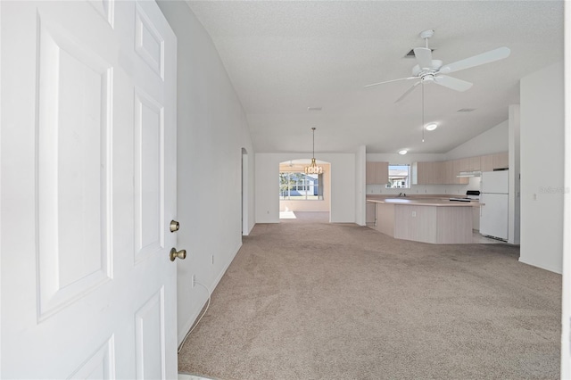 unfurnished living room with a textured ceiling, ceiling fan, lofted ceiling, and light colored carpet