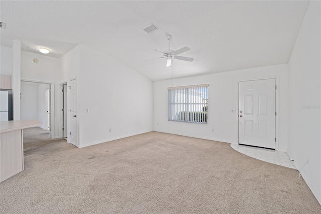 spare room with light carpet, ceiling fan, and vaulted ceiling