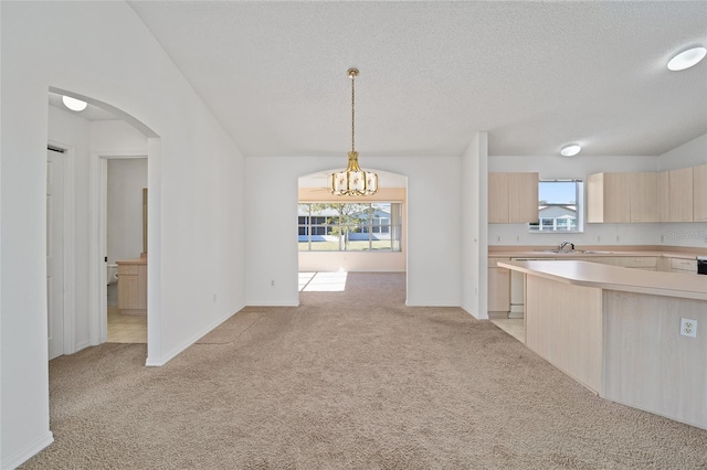 kitchen featuring light carpet, an inviting chandelier, a wealth of natural light, and light brown cabinets