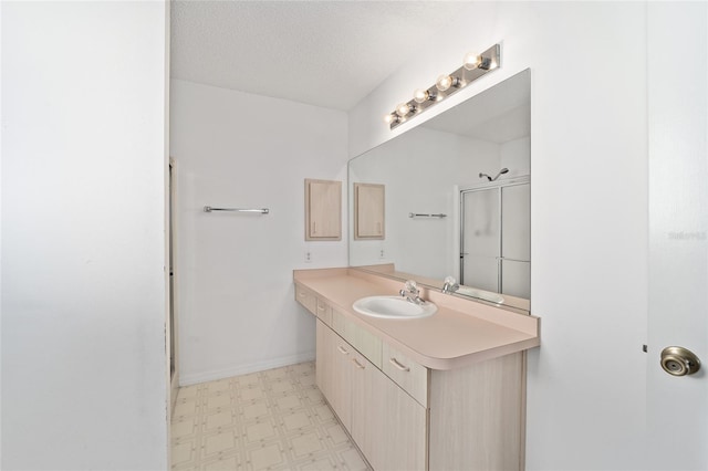 bathroom featuring a textured ceiling, an enclosed shower, and vanity