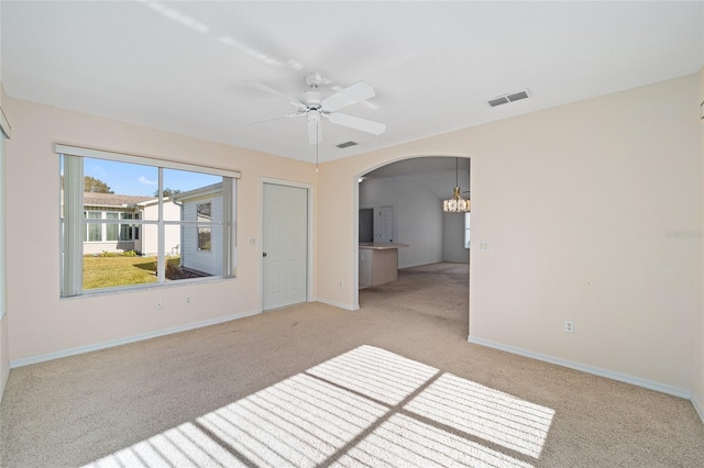 interior space featuring light colored carpet and ceiling fan with notable chandelier