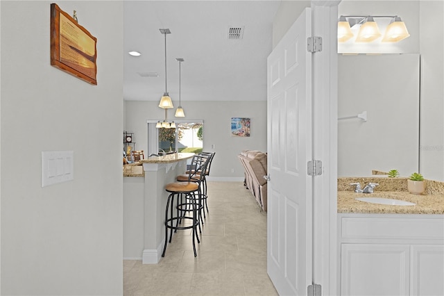 1741 Bonser Rd, Minneola, FL 34715 - kitchen featuring a kitchen bar, light stone countertops, light tile patterned floors, decorative light fixtures, and white cabinetry
