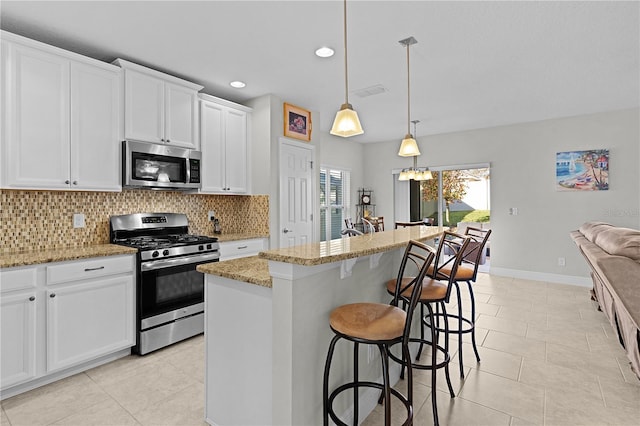 kitchen featuring white cabinets, a center island, stainless steel appliances, and hanging light fixtures