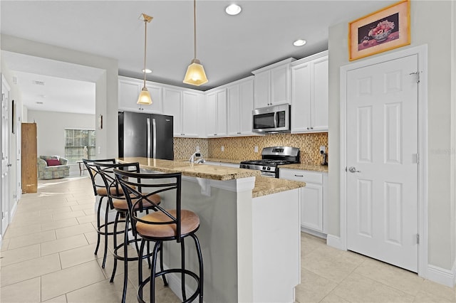 kitchen featuring a center island with sink, light stone counters, white cabinets, and stainless steel appliances