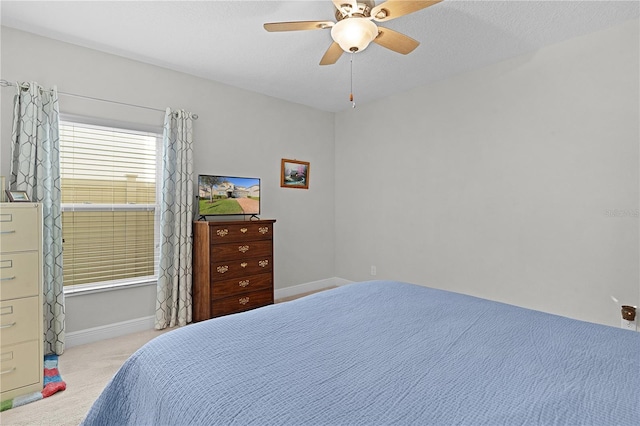 bedroom featuring ceiling fan, light carpet, and a textured ceiling