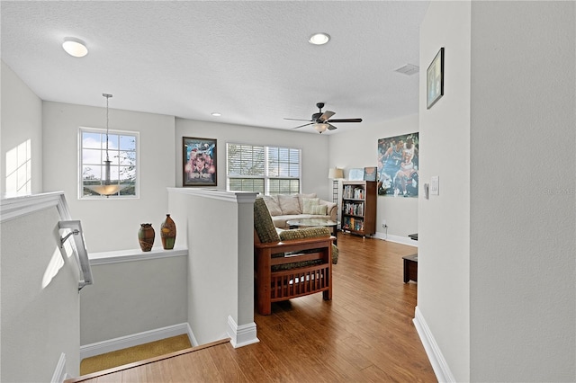 living room with hardwood / wood-style flooring, ceiling fan, a healthy amount of sunlight, and a textured ceiling