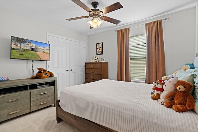 carpeted bedroom featuring ceiling fan and a closet