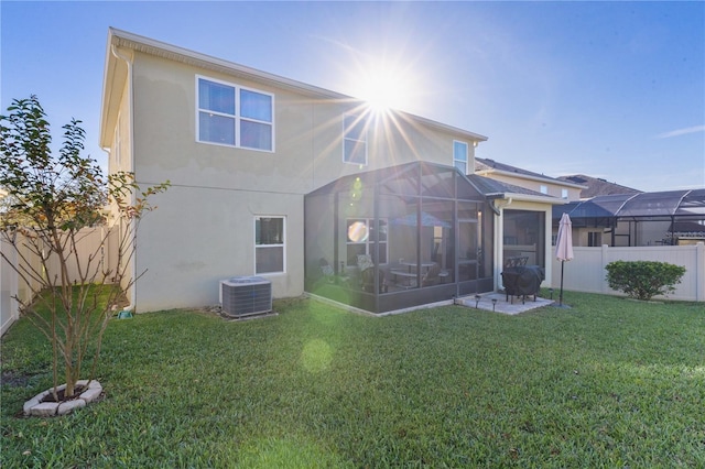 back of property with central AC unit, a sunroom, and a yard