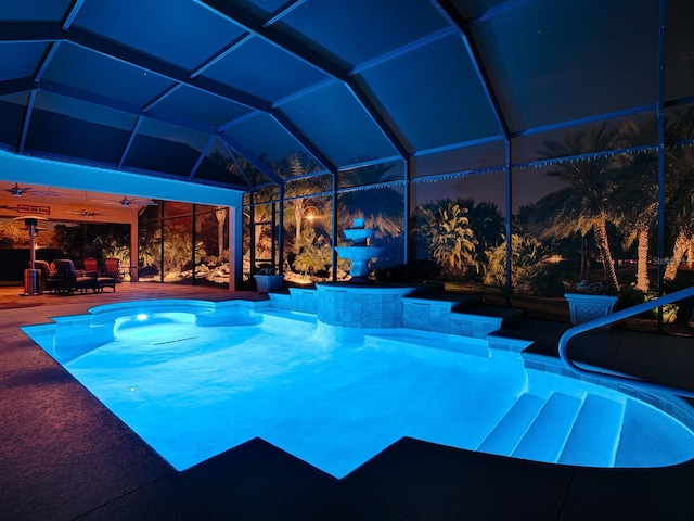 pool at night featuring ceiling fan, a patio area, and a lanai