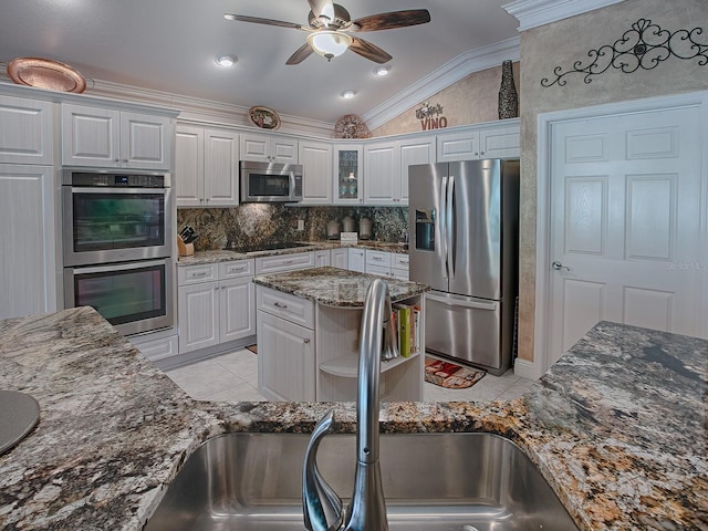 kitchen featuring lofted ceiling, sink, dark stone countertops, appliances with stainless steel finishes, and white cabinetry