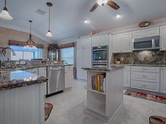 kitchen featuring a center island, sink, appliances with stainless steel finishes, decorative light fixtures, and white cabinetry