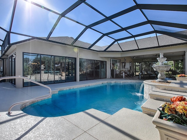 view of swimming pool with pool water feature, ceiling fan, a patio, and glass enclosure