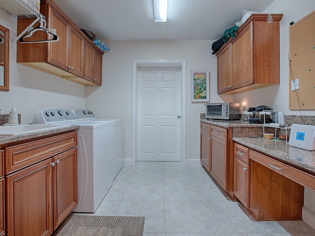 washroom with cabinets, washing machine and dryer, light tile patterned floors, and sink