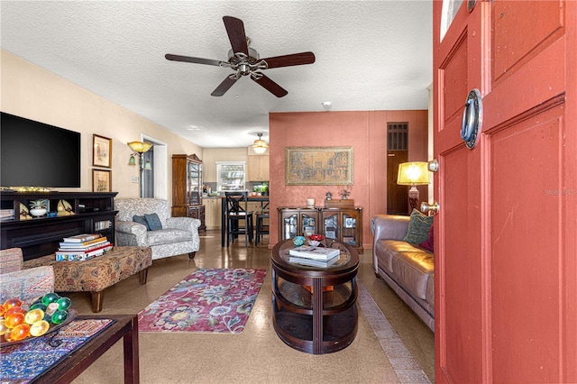 living room featuring ceiling fan and a textured ceiling