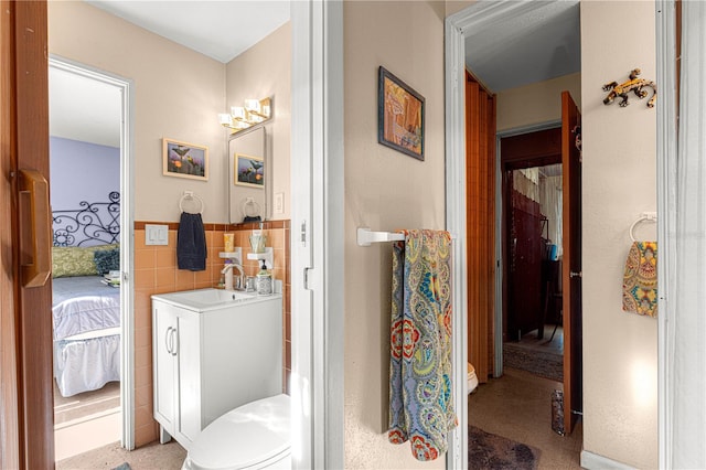 bathroom with vanity, toilet, and tile walls