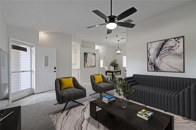 living room featuring lofted ceiling, light tile patterned floors, and ceiling fan with notable chandelier