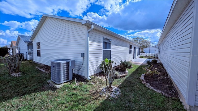 view of side of property with cooling unit and a lawn