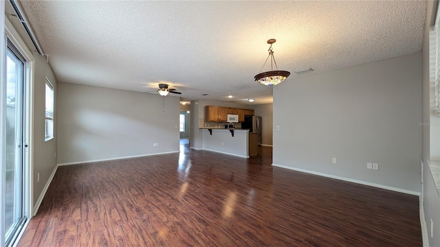 unfurnished living room with ceiling fan, dark hardwood / wood-style floors, and a textured ceiling