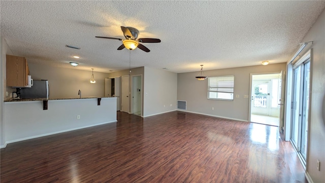 unfurnished living room with dark hardwood / wood-style flooring, sink, a textured ceiling, and ceiling fan