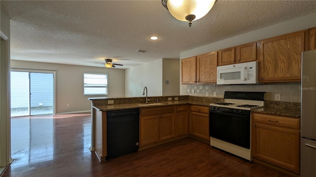 kitchen with dark wood-type flooring, sink, black dishwasher, range with gas stovetop, and decorative backsplash