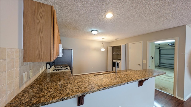 kitchen with sink, white appliances, a breakfast bar area, hanging light fixtures, and kitchen peninsula