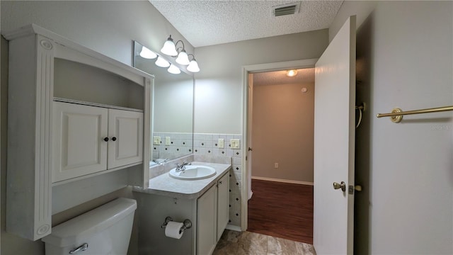 bathroom with vanity, backsplash, toilet, and a textured ceiling