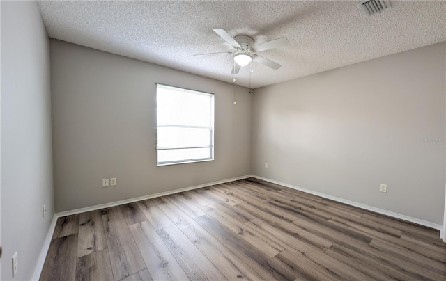 empty room with ceiling fan, hardwood / wood-style floors, and a textured ceiling