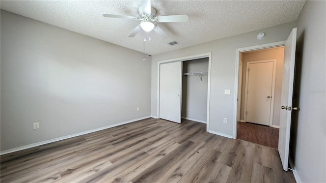 unfurnished bedroom featuring ceiling fan, a textured ceiling, a closet, and light wood-type flooring