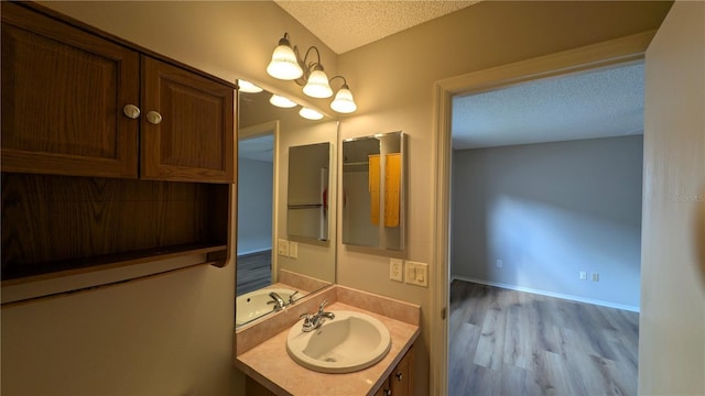 bathroom featuring hardwood / wood-style flooring, vanity, and a textured ceiling