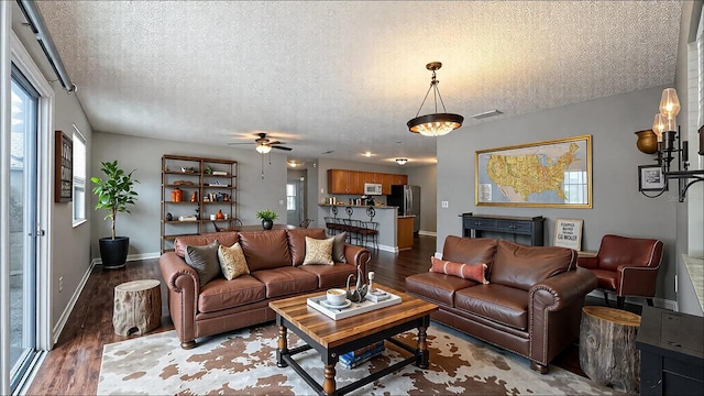 3449 Roanoke St, The Villages, FL 32162 - living room featuring a textured ceiling, baseboards, ceiling fan, and wood finished floors