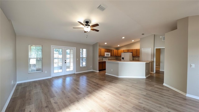 kitchen with french doors, lofted ceiling, a center island, light wood-type flooring, and white appliances