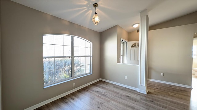 empty room featuring wood-type flooring and vaulted ceiling